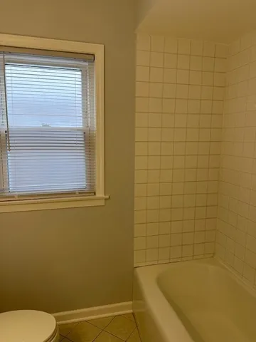 a bathroom with a blue tub shower and a toilet