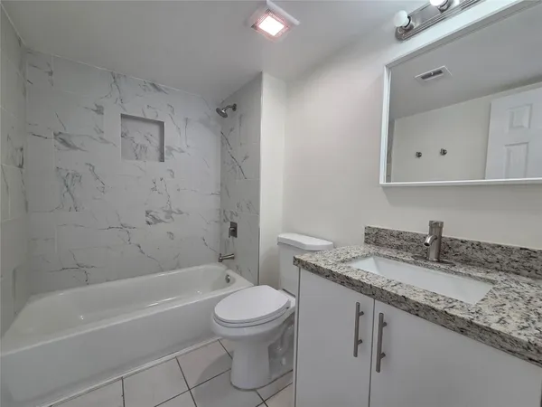 a bathroom with a granite countertop sink a toilet and bathtub