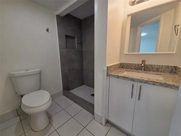 a bathroom with a granite countertop toilet sink and mirror