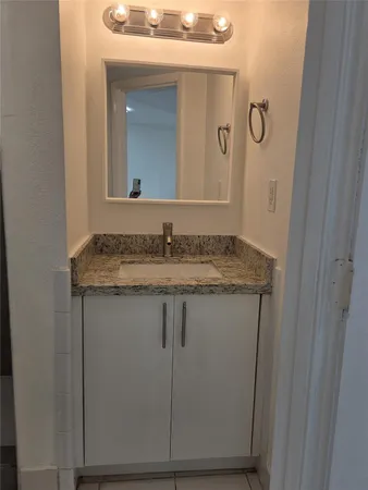 a bathroom with a granite countertop sink and a mirror