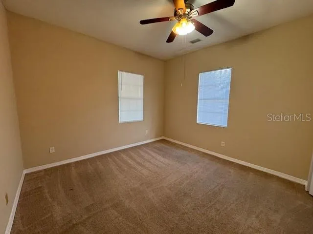 an empty room with a window and a fan