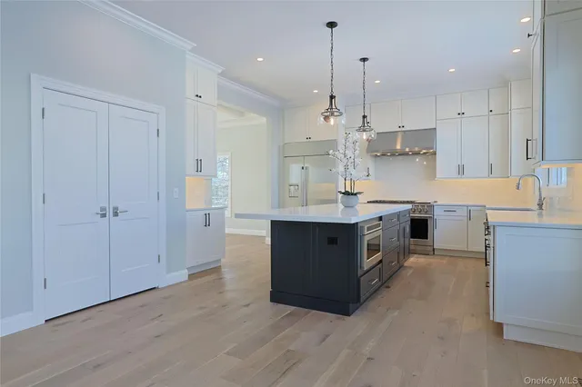 a large kitchen with stainless steel appliances granite countertop a large counter top a sink a stove and a refrigerator