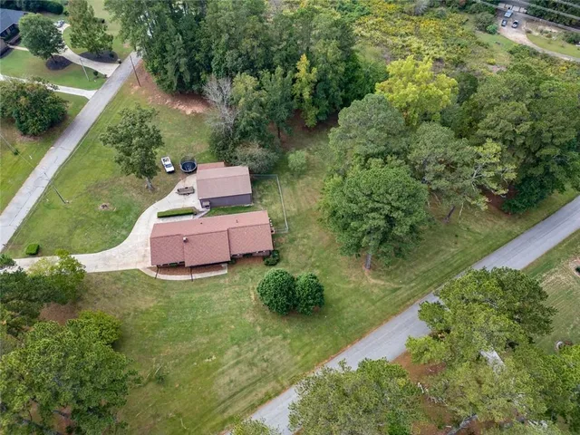 an aerial view of residential house with outdoor space and trees all around