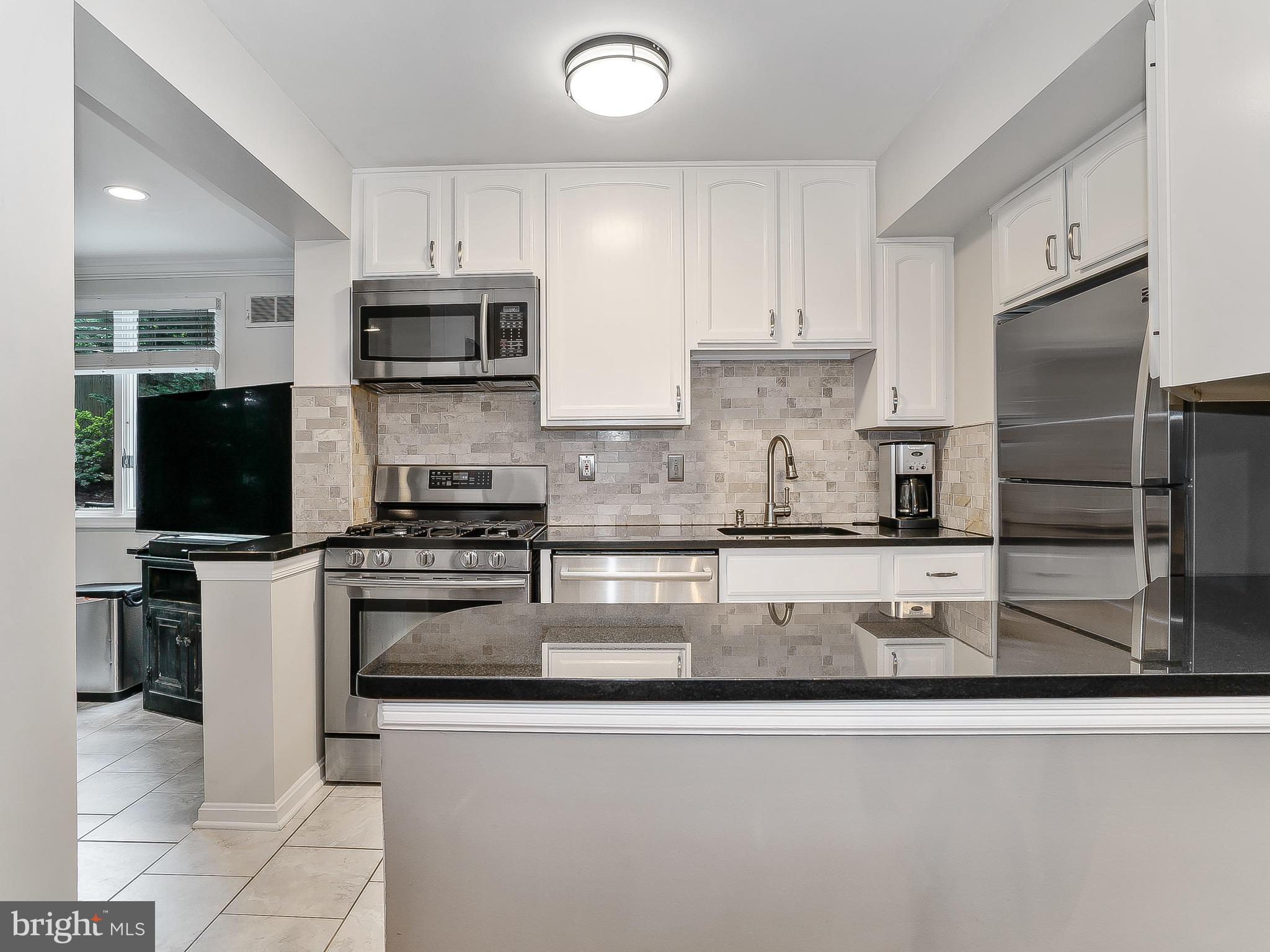 10205 Carson Place Silver Spring, MD 20901 - Photo 15 of 30 a kitchen with stainless steel appliances granite countertop a stove top oven a sink and a refrigerator
