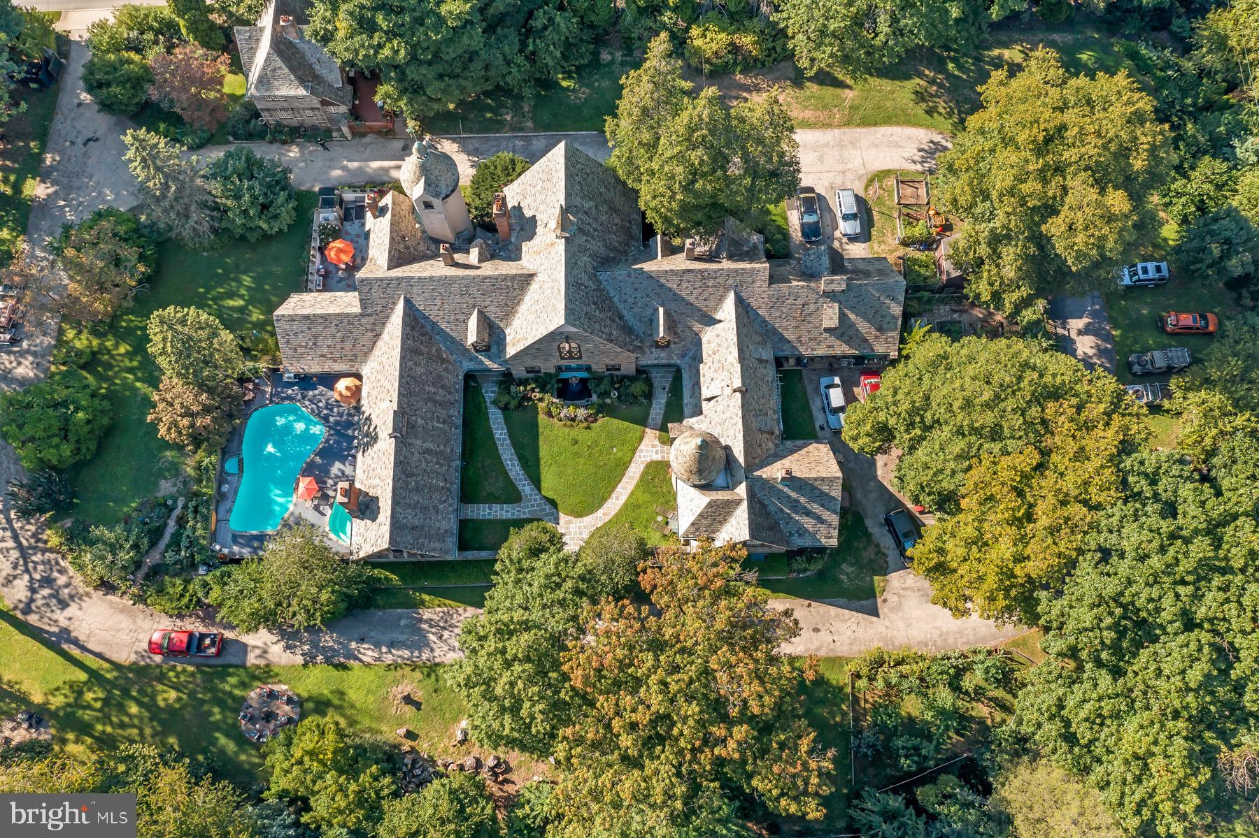an aerial view of a house with swimming pool and large trees