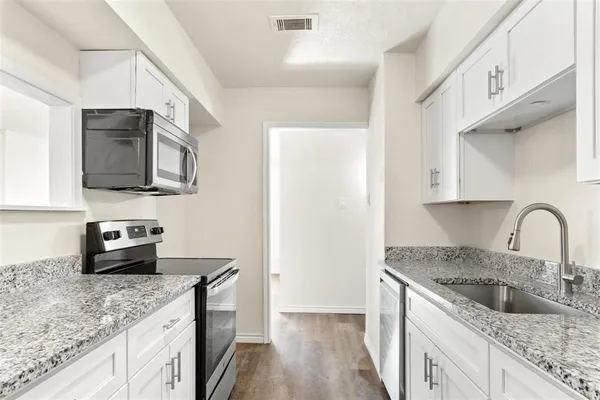 a kitchen with stainless steel appliances granite countertop a sink a stove top oven a counter space and cabinets