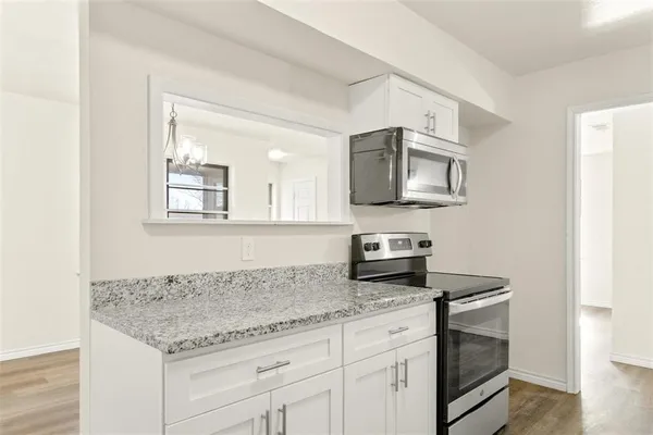 a kitchen with granite countertop a sink stainless steel appliances and white cabinets