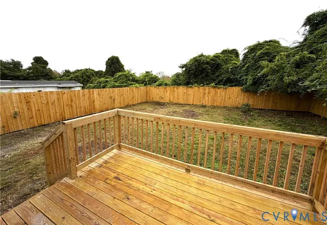 a view of wooden deck and lake with trees in the background