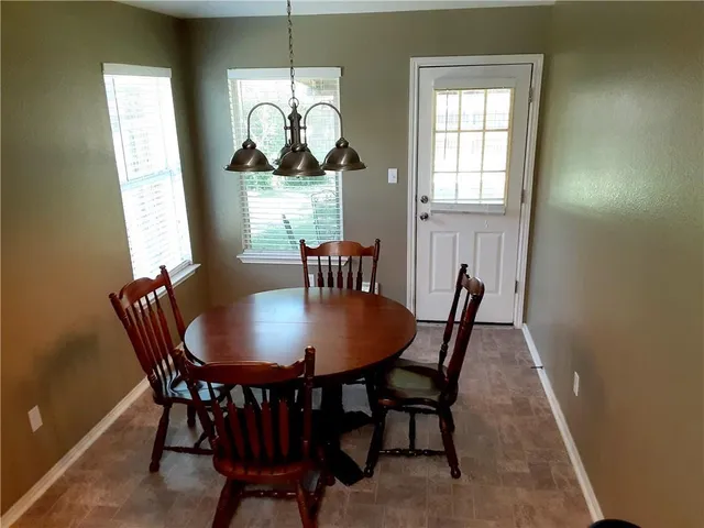 a dining room with furniture a rug a potted plant and a chandelier