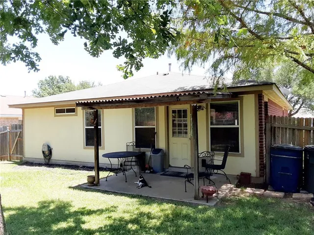 a view of a backyard with large trees and wooden fence