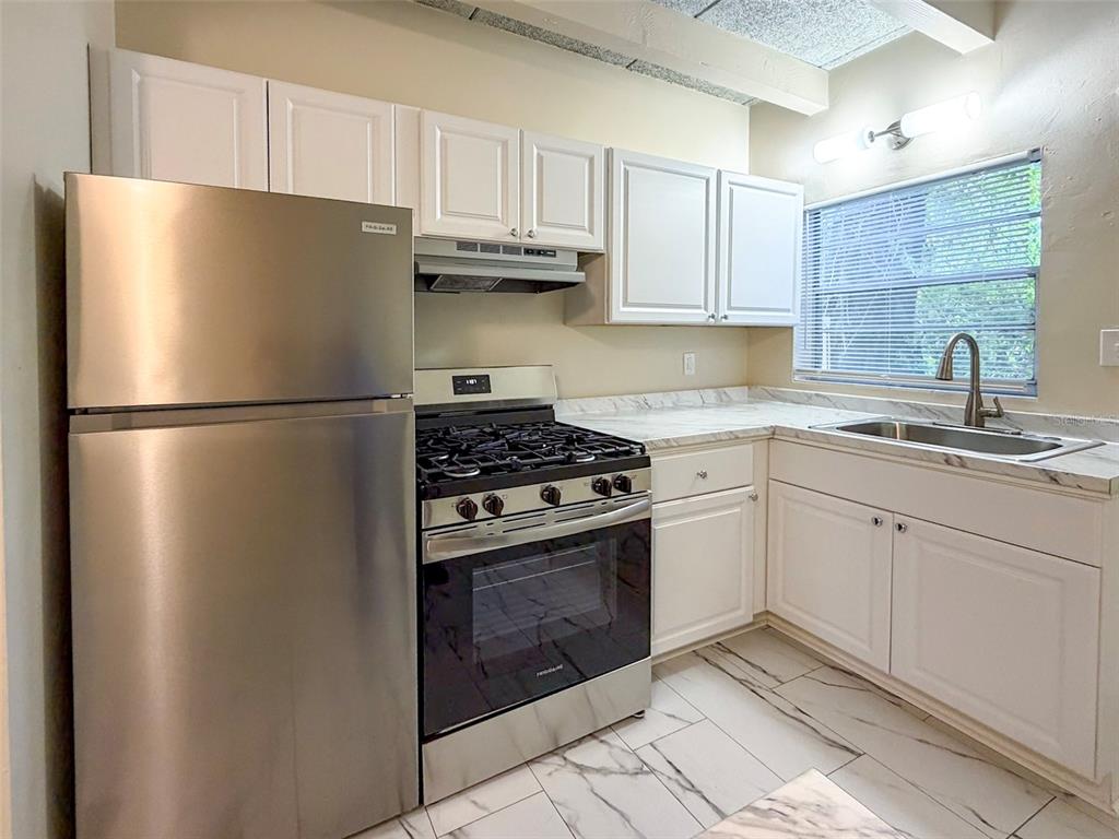 219 Northwest 3rd Avenue, Unit B Gainesville, FL 32601 - Photo 8 of 20 a kitchen with cabinets stainless steel appliances and a sink