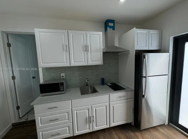 a kitchen with appliances a refrigerator and cabinets