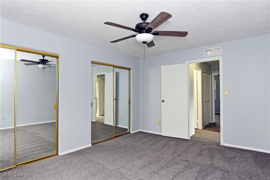 2276 Raber Road, Unit F Uniontown, OH 44685 - Photo 18 of 30 Unfurnished bedroom featuring a textured ceiling, two closets, a ceiling fan, and dark carpet