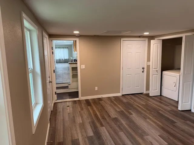 a view of a hallway with wooden floor and a refrigerator