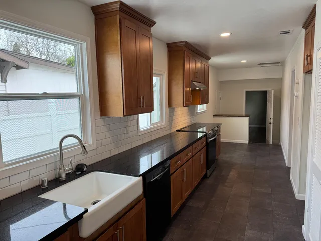 a large kitchen with a large counter top sink and stainless steel appliances