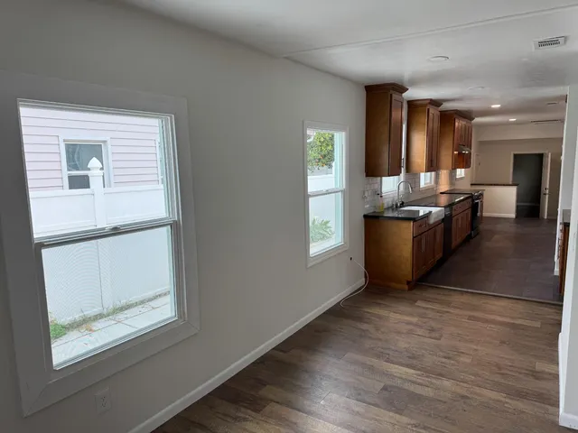 a living room with stainless steel appliances granite countertop furniture and a wooden floor