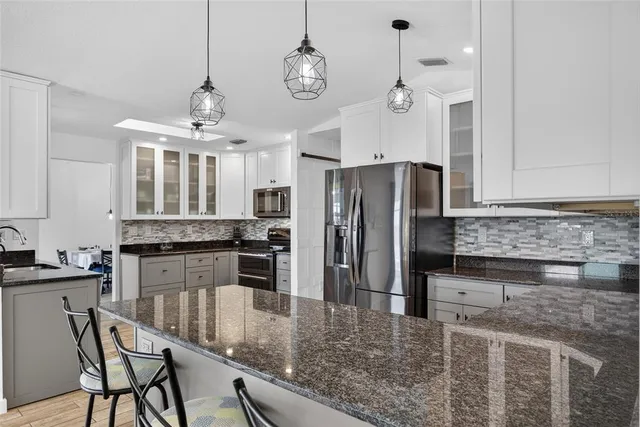 a kitchen with stainless steel appliances granite countertop a sink refrigerator and cabinets