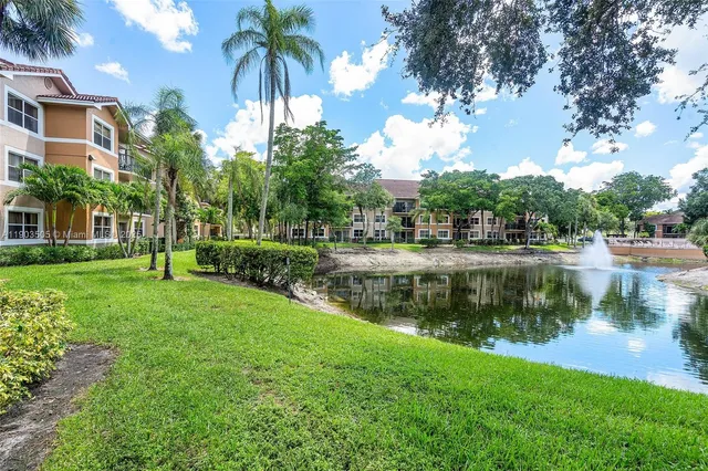 a view of a lake with a yard and palm trees