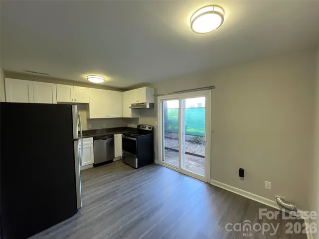 a kitchen with stainless steel appliances granite countertop a refrigerator a sink dishwasher a stove and a large window with wooden floor