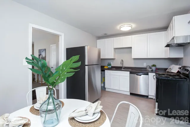 a kitchen with stainless steel appliances a dining table a microwave a stove and cabinets