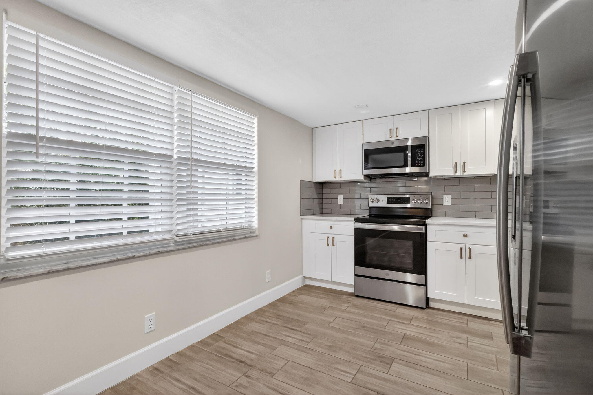 545 Oaks Lane, Unit 409 Pompano Beach, FL 33069 - Photo 6 of 25 a kitchen with a window a sink and a microwave