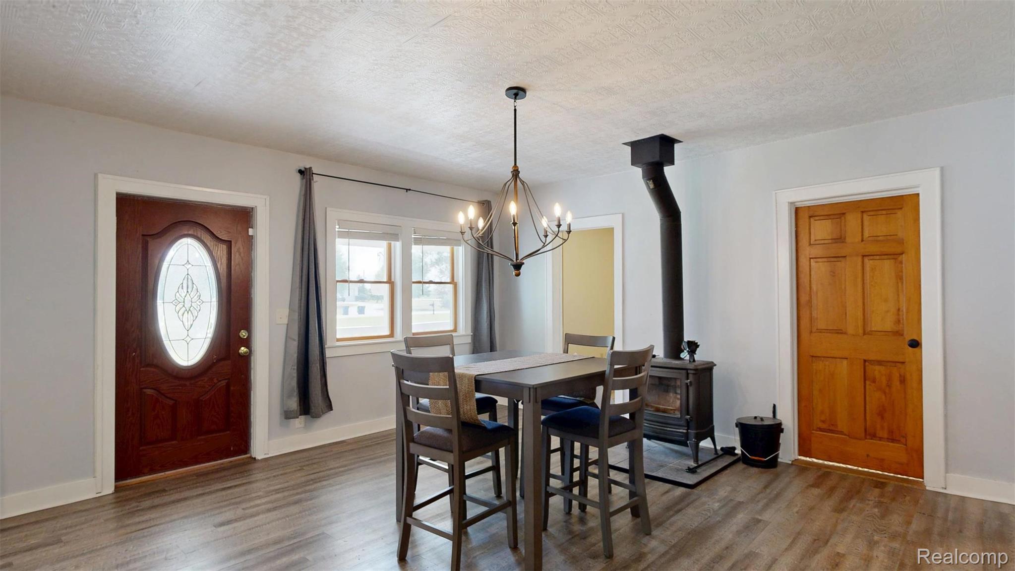 12930 Wilkinson Road Freeland, MI 48623 - Photo 44 of 76 Wood-finish flooring, central light fixture, multi-pane windows, wood-burning stove, and solid wood doors