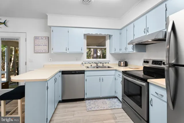 a kitchen with stainless steel appliances granite countertop a refrigerator and a wooden floors