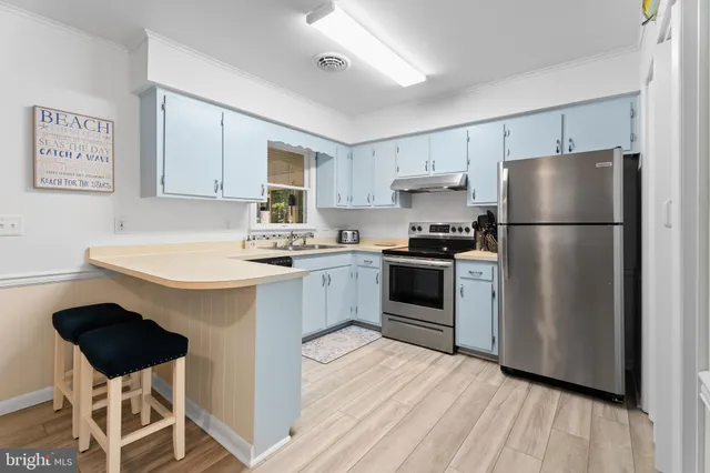 a kitchen with a refrigerator a stove a sink dishwasher and white cabinets with wooden floor