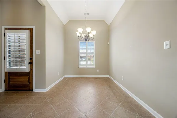 a view of an empty room with chandelier fan and fire place