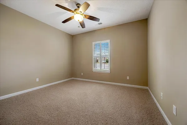 an empty room with windows and fan