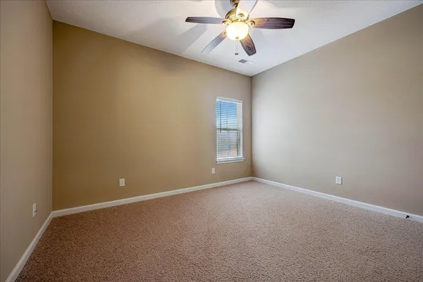 an empty room with a chandelier fan and windows