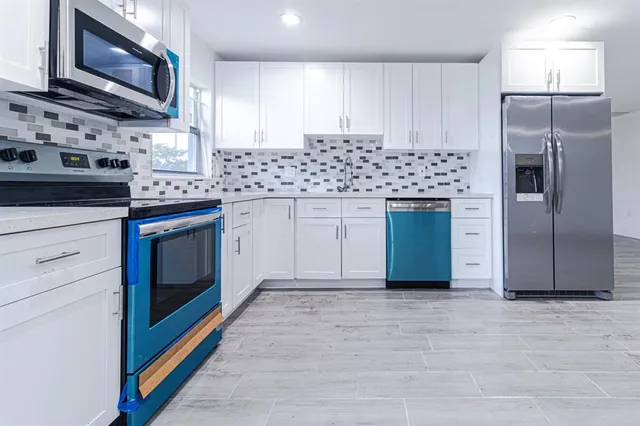 a kitchen with stainless steel appliances granite countertop a stove a sink and a refrigerator