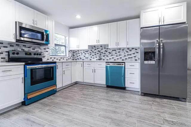 a kitchen with granite countertop a refrigerator stove and microwave