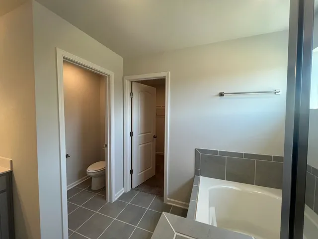 a bathroom with a granite countertop bathtub shower and toilet