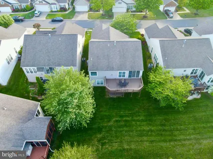 a view of a white house next to a yard with plants and trees