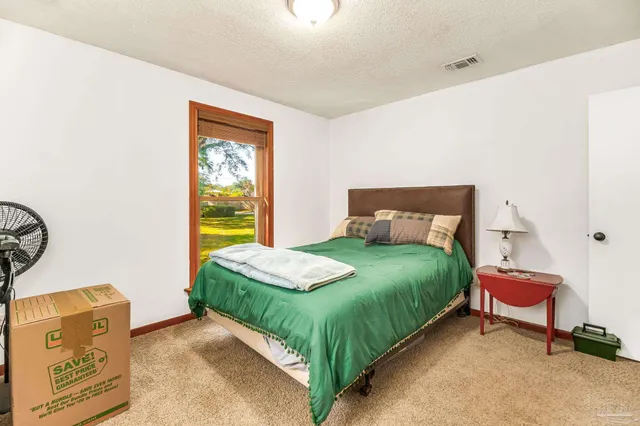 a bedroom with a bed a dresser and a window