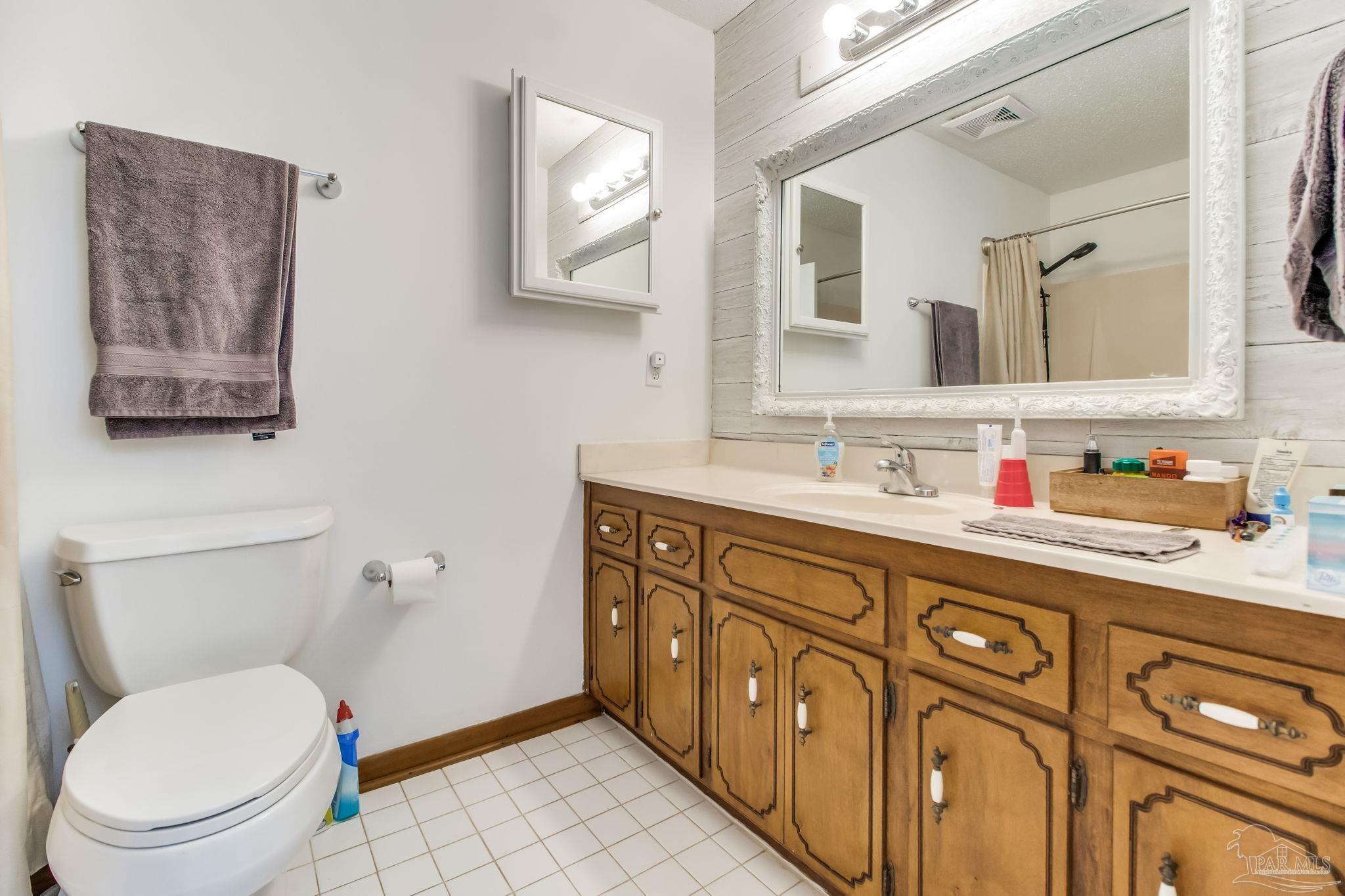 4640 Bessinger Lane Pace, FL 32571 - Photo 28 of 54 a bathroom with a granite countertop toilet sink and mirror