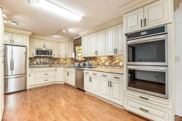 a kitchen with granite countertop white cabinets and stainless steel appliances
