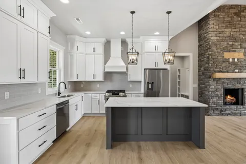 a large kitchen with cabinets a sink dishwasher and a stove with wooden floor