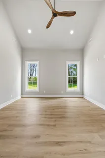 a view of an empty room with window and wooden floor