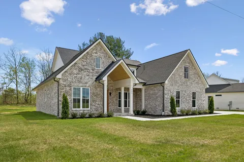a view of a house with a big yard plants and large trees