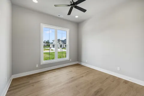 an empty room with wooden floor fan and windows
