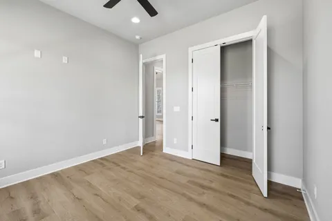 an empty room with wooden floor and a ceiling fan