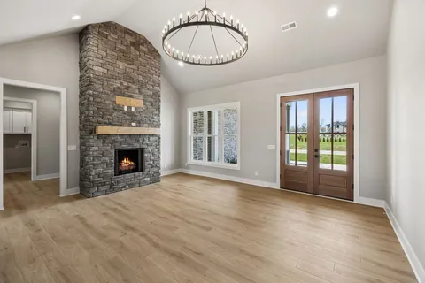 a view of an empty room with glass door and wooden floor