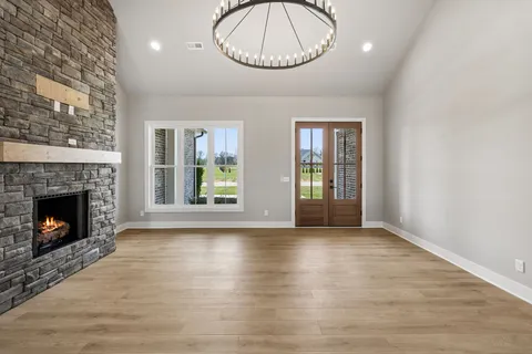 a view of an empty room with wooden floor fireplace and a window