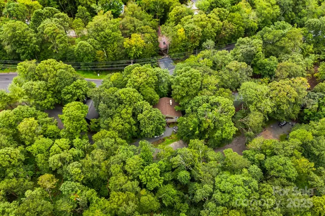 an aerial view of residential house with outdoor space and trees all around