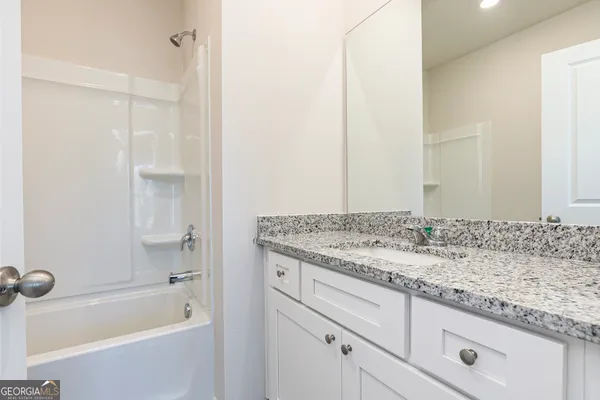 a bathroom with a granite countertop sink and a bathtub
