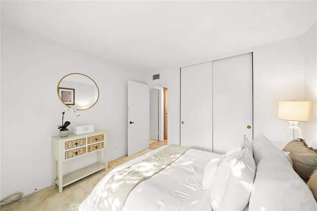 a bedroom with a bed a mirror a lamp and a table