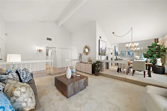 a living room with furniture and a large mirror next to a window