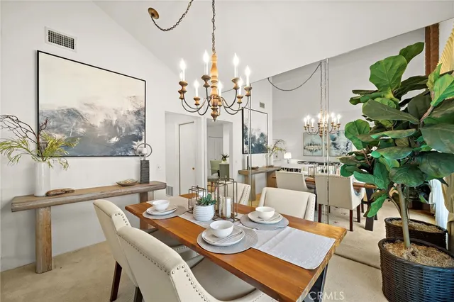 a view of a dining room with furniture a potted plant and a chandelier